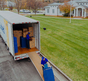 A mover unloading a pad wrapped items from a United Van Lines trailer.