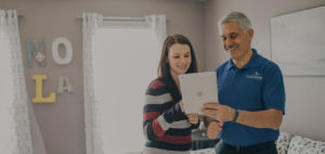 A man talking to a woman showing her information on his tablet.