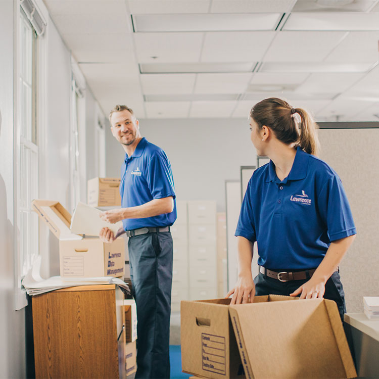 Two movers looking at each other while unboxing boxes.