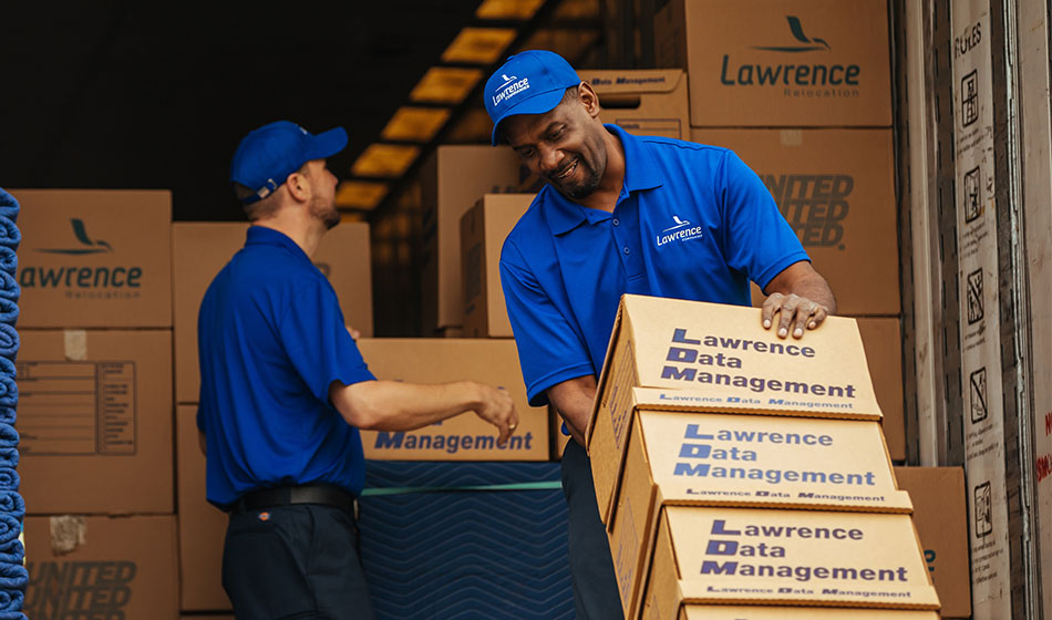 A mover unloads boxes off of a truck with a dolly.