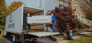Two movers unloading a sofa out of a moving truck.