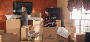 A child helps his mother unpack boxes with the father in the background.