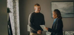 A woman talking to a man showing information on her tablet