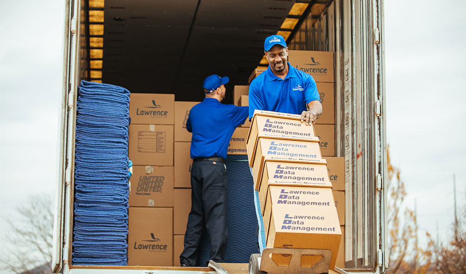 A Mover unloading five boxes off a truck with a dolly.