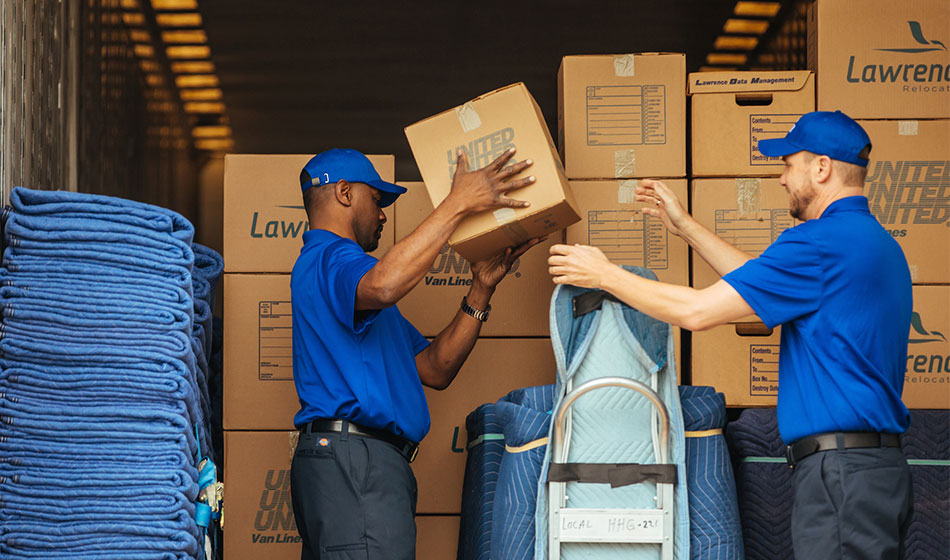 Two movers picking up boxes on the back of a truck