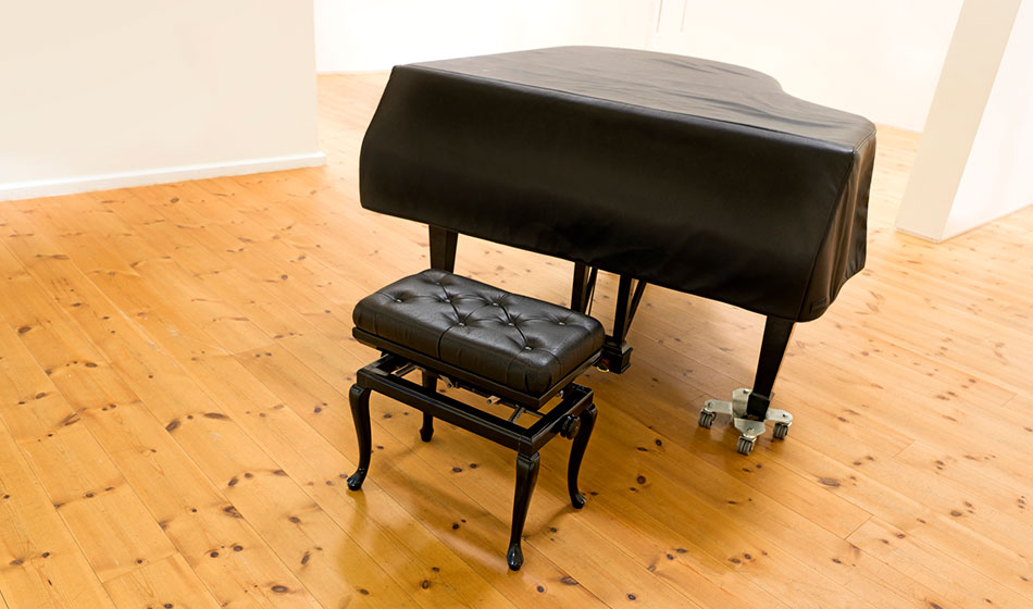 A piano with a bench is sitting in a room.