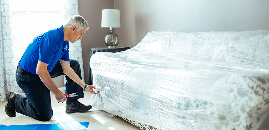 A mover plastic wrapping a sofa.