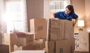 A female mover loads a wrapped package into a box.