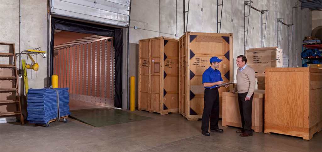 Two movers talk in a warehouse.