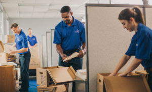 A group of movers unload boxes in an office.