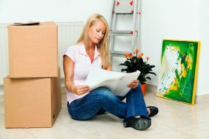 Woman reading important papers while sitting on floor in front of moving boxes.