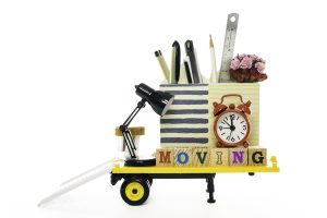 Office supplies, small lamp, clock, pencil holder on a small yellow.cart