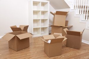 Empty room with empty bookcase and moving boxes in the foreground.