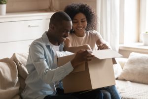Couple sit on a couch with a moving box after a move.