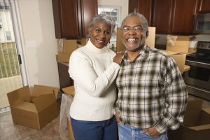 Mature woman and man in kitchen with moving boxes in the background as they prepare to move out.