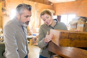 Man and woman looking closely at an antique wooden box determining how to properly pack it for a move.