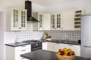 Small kitchen with white cabinets and white subway tile and black countertops.