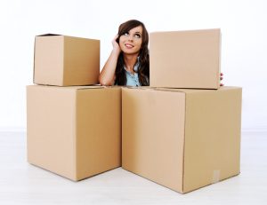 Woman with her elbow on a moving box sitting in a wondering or thinking position