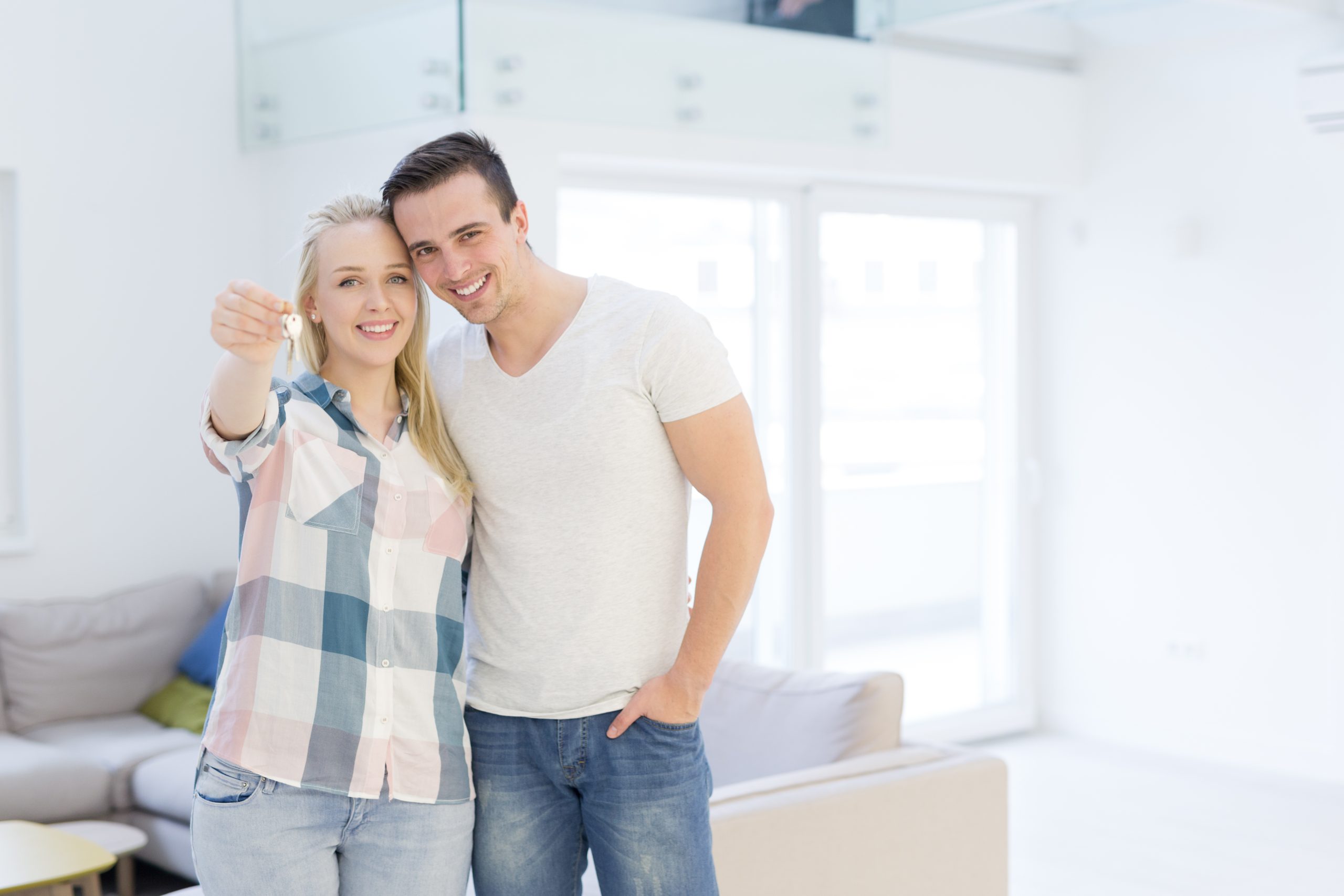 Happy smiling young couple hugging while showing the keys of their new house