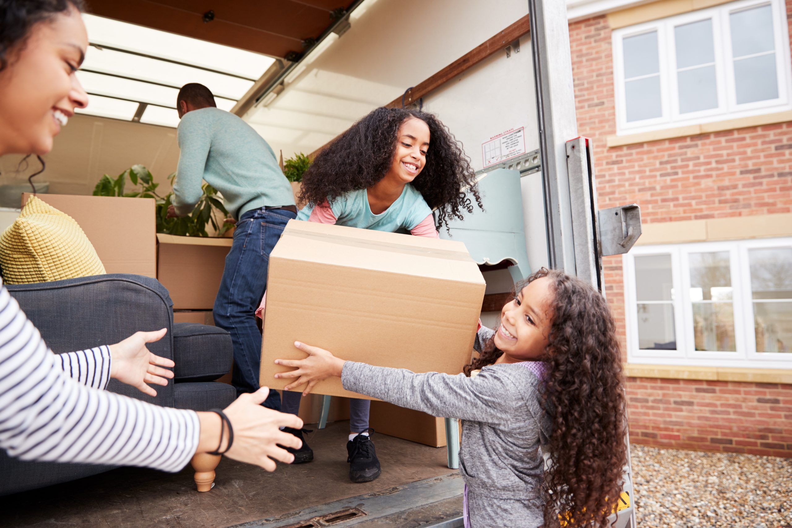 Family Unloading Furniture From moving Truck Into New Home