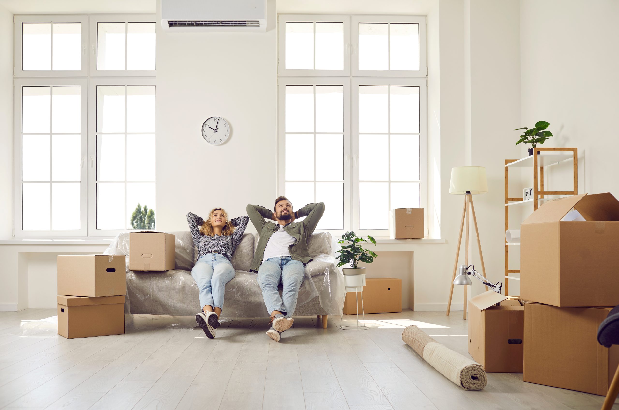 Happy couple take break and sit on couch while moving in their newly bought house