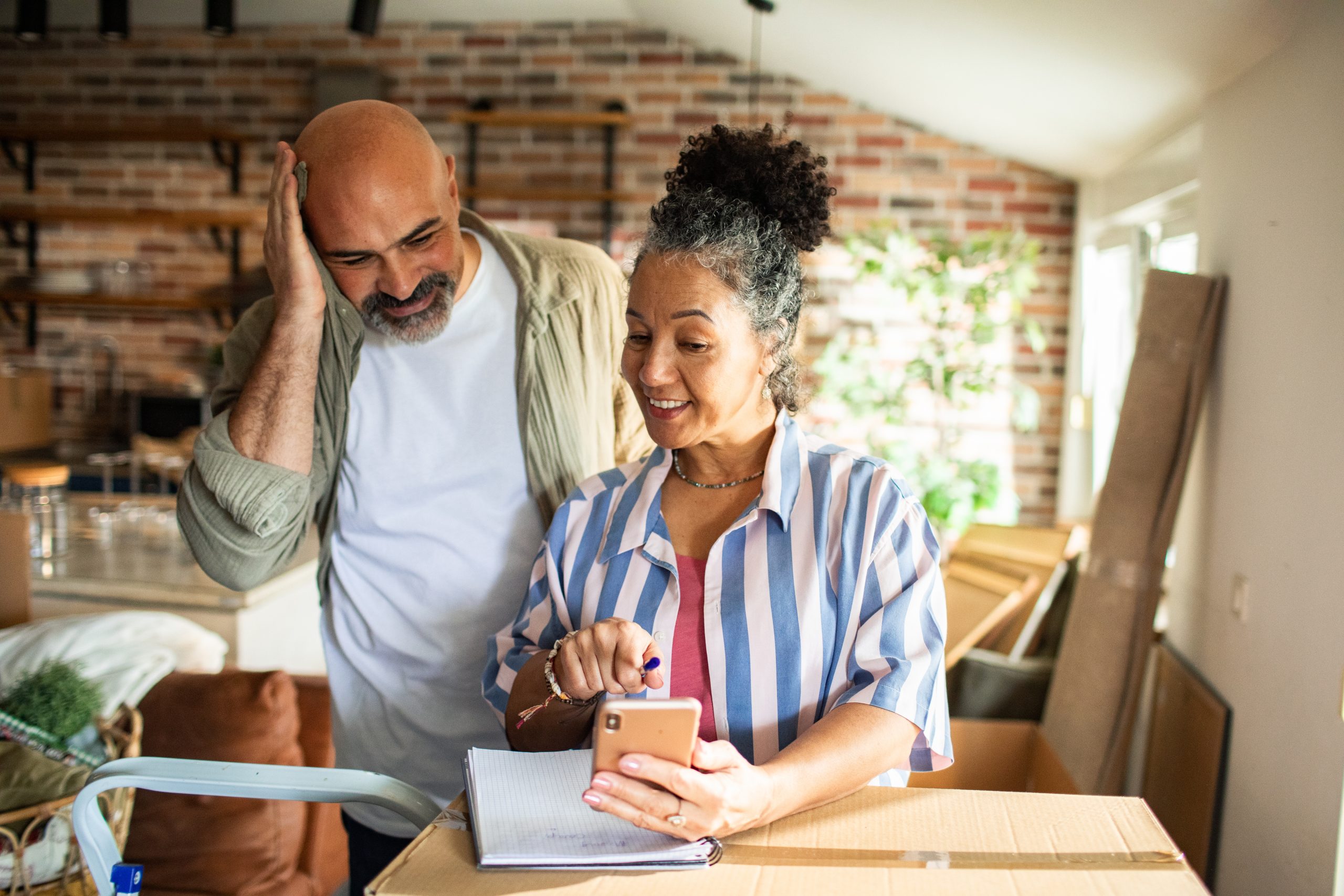 Smiling mature couple planning a moving budget in a kitchen