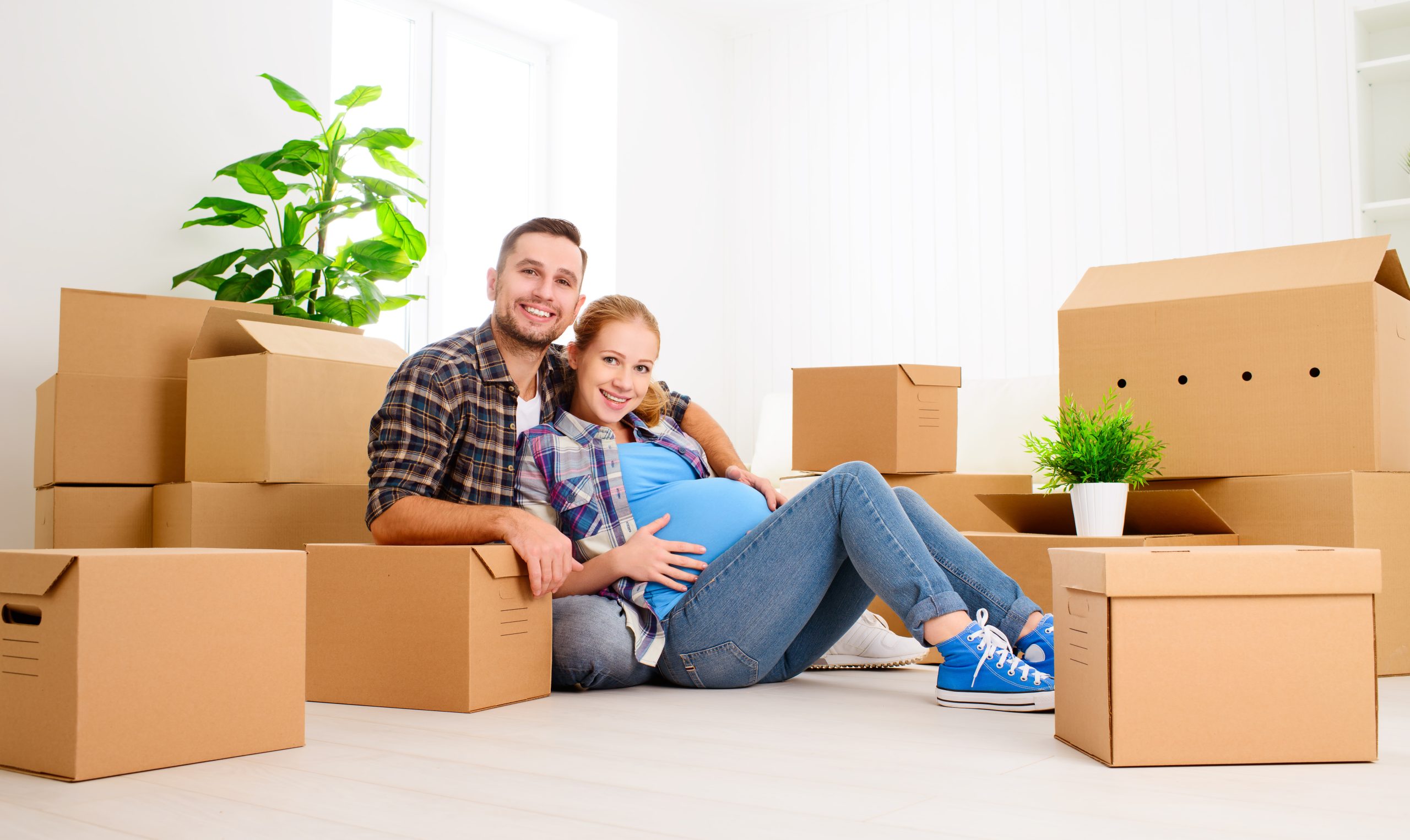 moving to a new home. young family pregnant wife and husband with cardboard boxes